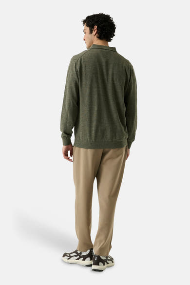 Olive green crewneck sweater with ribbed cuffs and hem, back view, worn with beige trousers and patterned sneakers