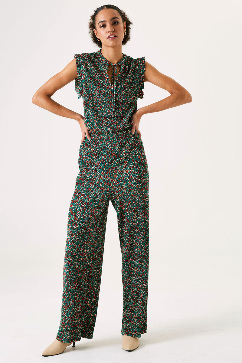 Pantalon vert imprimé de GARCIA, avec un motif floral rouge et beige, porté avec des chaussures à talons beiges.
