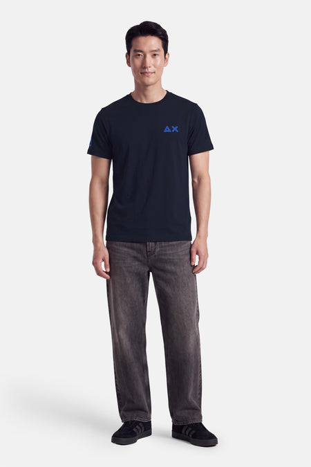 T-shirt bleu à manches courtes par SUN 68, avec logo brodé sur la poitrine, porté en look casual avec jeans gris et baskets noires