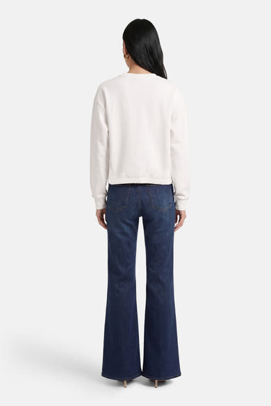 Sweat blanc à col rond de ADORE, porté avec un jean évasé et des talons hauts, vue de dos.