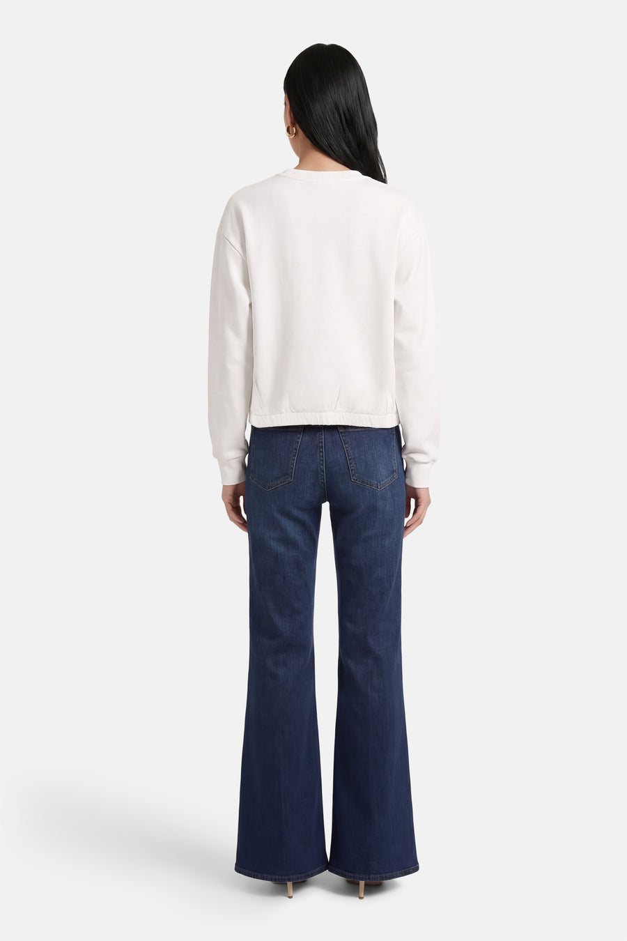 Sweat blanc à col rond de ADORE, porté avec un jean évasé et des talons hauts, vue de dos.