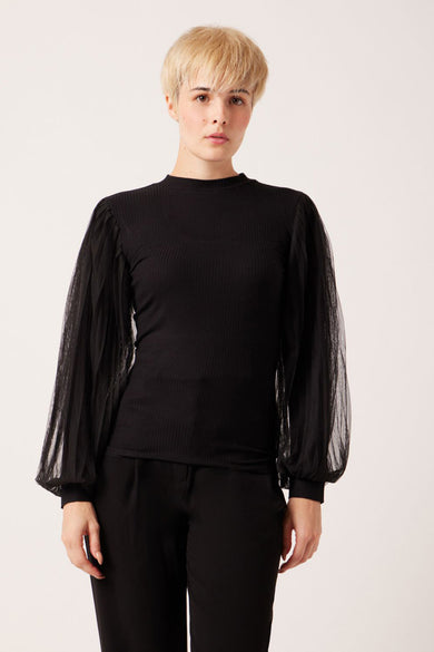 Black ribbed long-sleeve top with sheer puffed sleeves, front view, model wearing black pants
