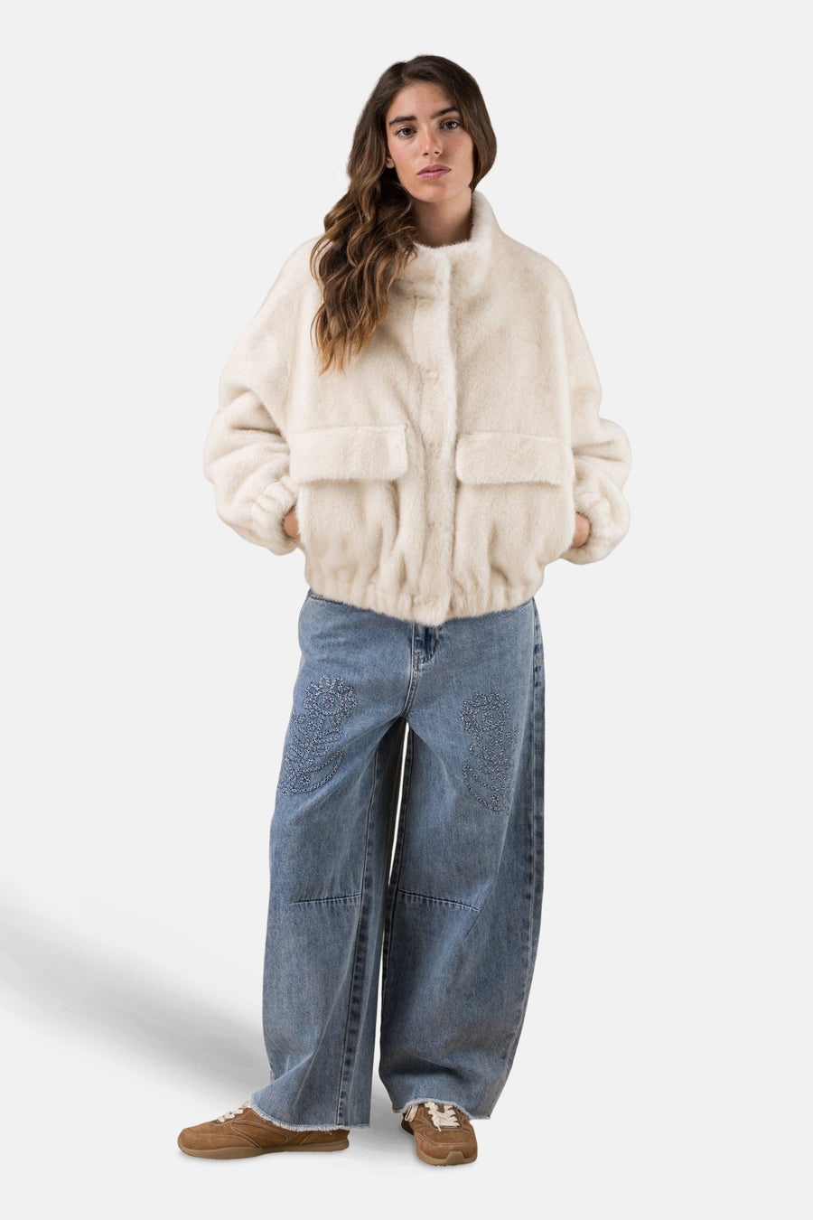 Jean bleu clair délavé d'ADORE, avec motifs brodés floraux sur les jambes, porté avec une veste en fausse fourrure blanche.
