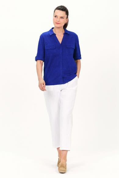 Chemisier bleu à manches courtes de CAROLL, porté avec un pantalon blanc et des mocassins marron.