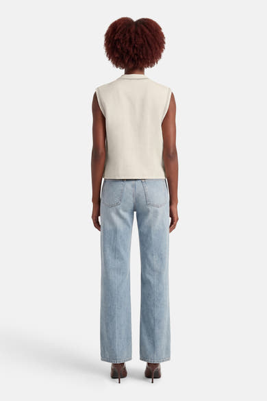 Ecru hemdje van ADORE, met gestikte afwerkingen, gedragen met een wijde blauwe jeans en hoge hakken.