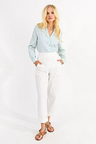 Pantalon coloré blanc de Molly Bracken, porté avec une chemise rayée bleu clair et des sandales en cuir marron.