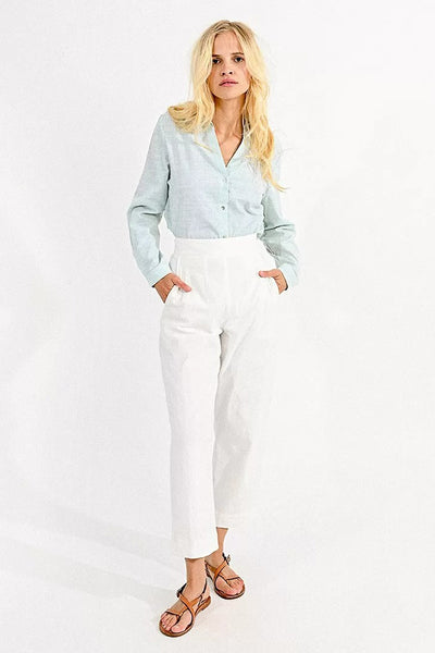 Pantalon coloré blanc de Molly Bracken, porté avec une chemise rayée bleu clair et des sandales en cuir marron.