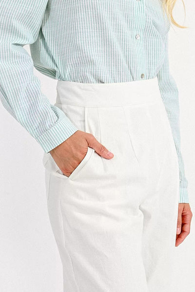 Pantalon blanc de Molly Bracken, avec taille haute et poches, porté avec une chemise rayée.