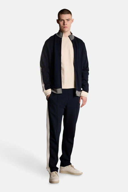 Beige T-shirt met korte mouwen van Lyle & Scott, gedragen met een trainingsjack en een marineblauwe joggingbroek.