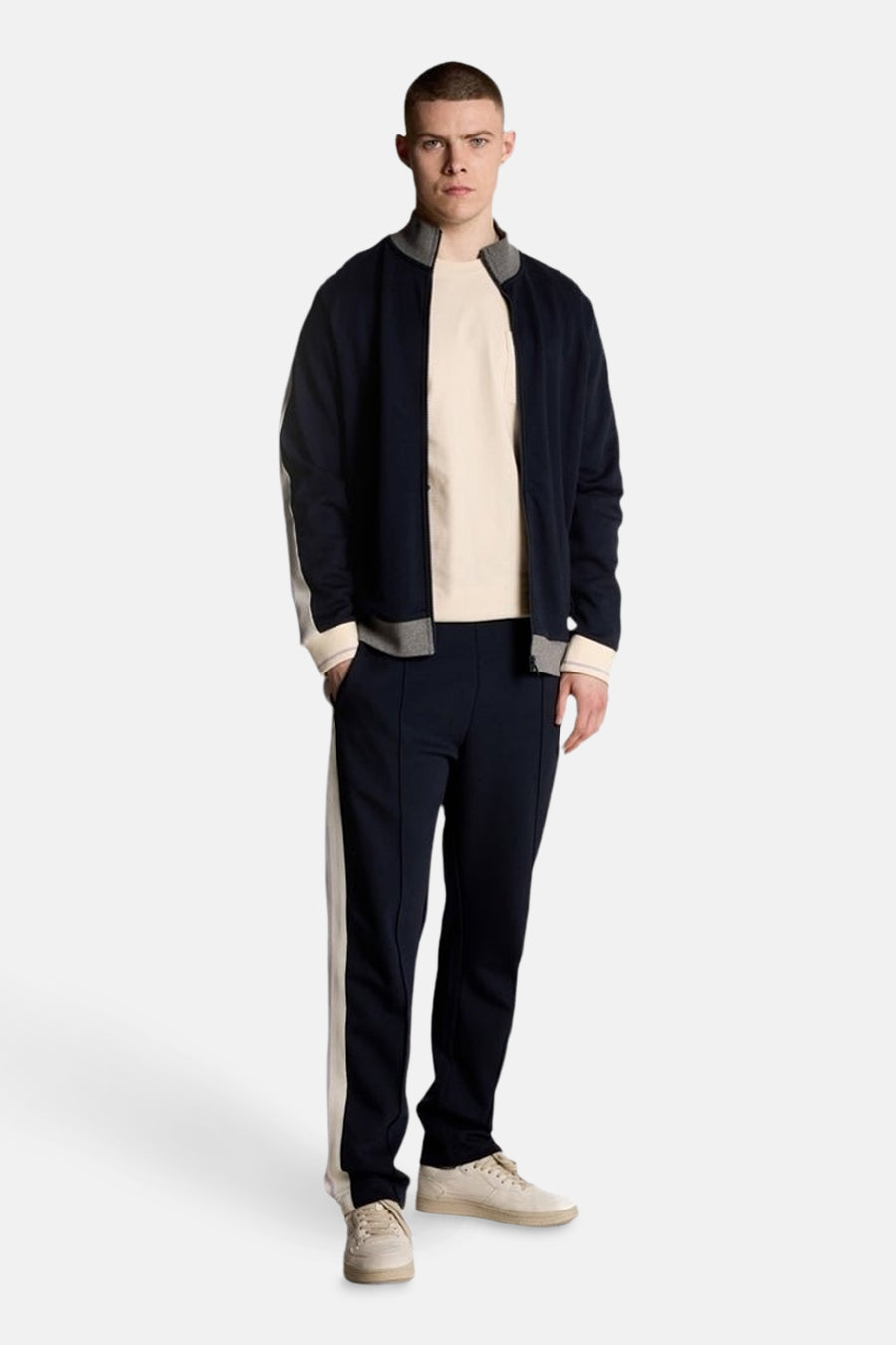 Beige T-shirt met korte mouwen van Lyle & Scott, gedragen met een trainingsjack en een marineblauwe joggingbroek.