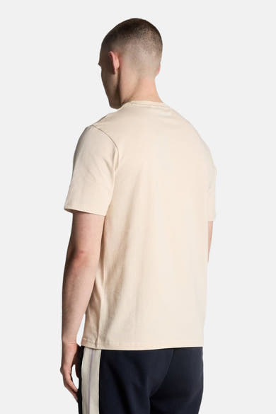 T-shirt beige à manches courtes de LYLE & SCOTT, vue de dos, porté avec un pantalon de survêtement bleu marine.