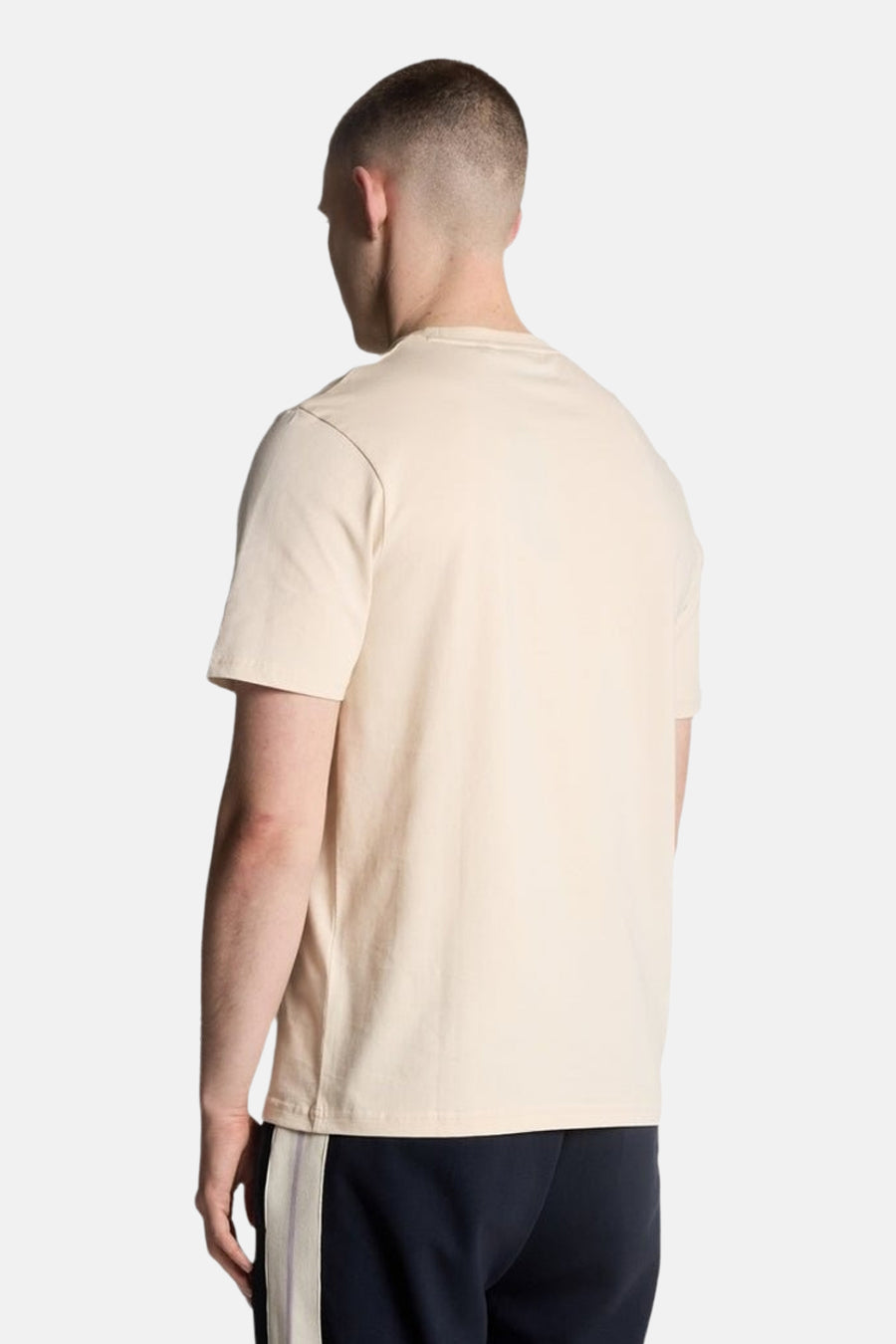 T-shirt beige à manches courtes de LYLE & SCOTT, vue de dos, porté avec un pantalon de survêtement bleu marine.