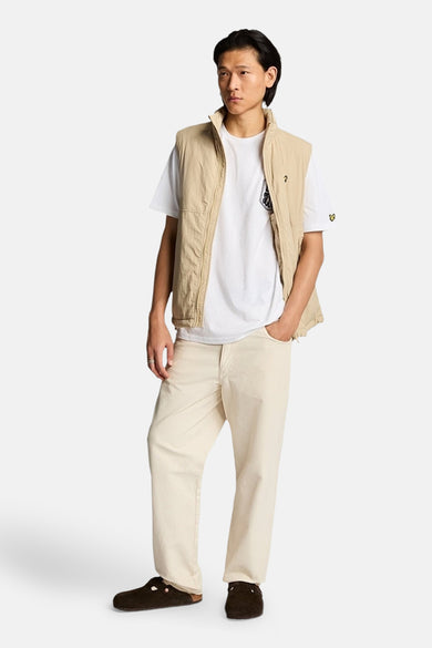 Wit T-shirt met korte mouwen van LYLE & SCOTT, gedragen met een beige vest en een gebroken witte broek.
