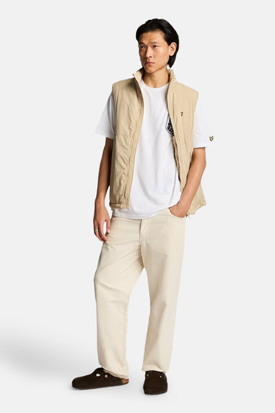 Wit T-shirt met korte mouwen van LYLE & SCOTT, gedragen met een beige vest en een gebroken witte broek.