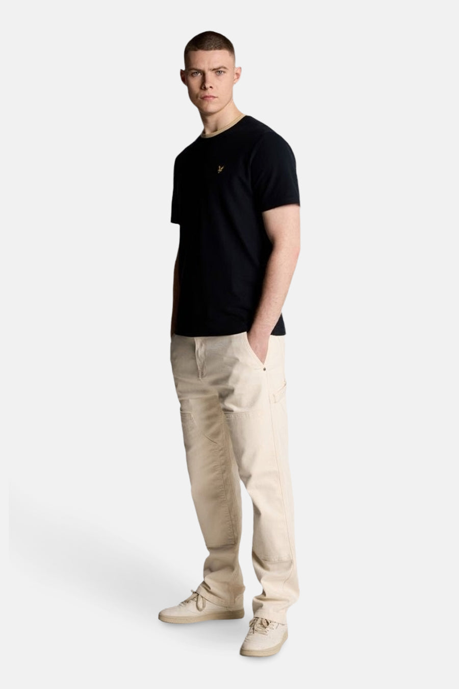 T-shirt à manches courtes bleu de LYLE & SCOTT, porté avec un pantalon beige et des chaussures de sport assorties.