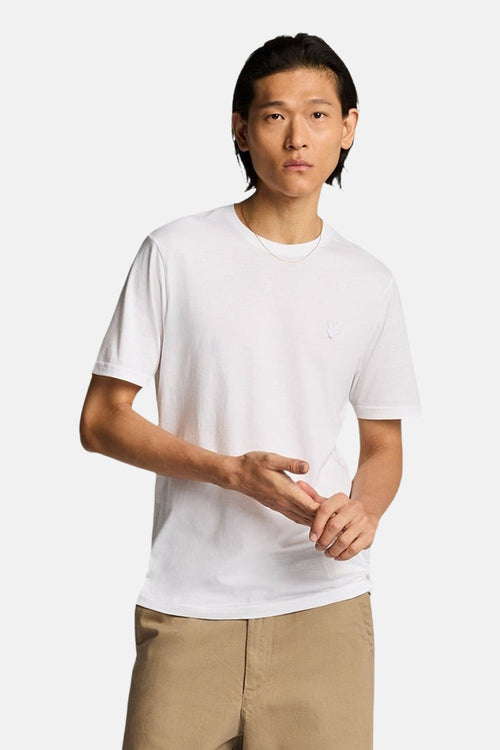 T-shirt blanc à manches courtes de LYLE & SCOTT, porté avec un pantalon chino beige et une chaîne en or.