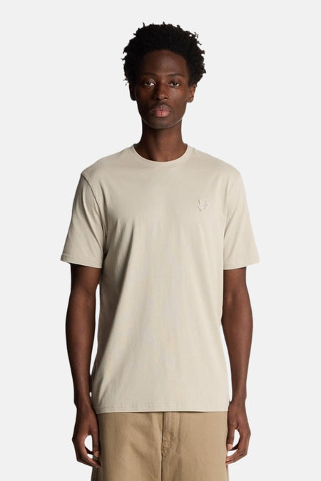 Beige T-shirt met korte mouwen van LYLE & SCOTT, van achteren gezien, gedragen met een camelkleurige korte broek.