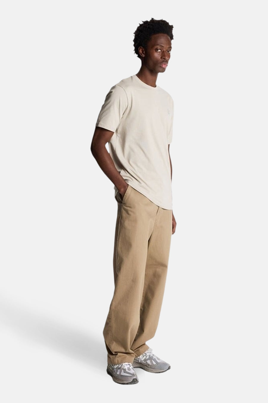 Beige T-shirt met korte mouwen van LYLE & SCOTT, gedragen met een bruine broek en grijze sportschoenen.