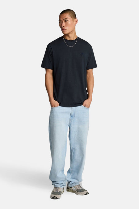 Blauw T-shirt met korte mouwen van LYLE & SCOTT, gedragen met een wijde jeans en grijze sneakers.