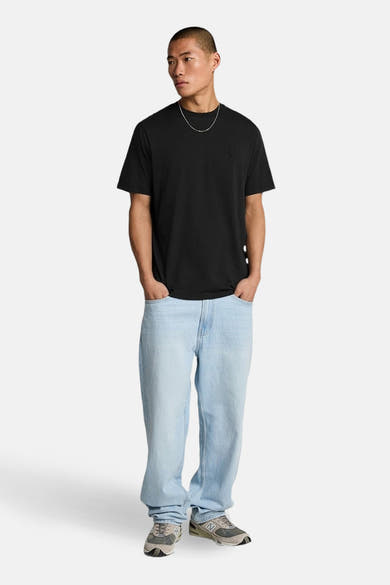 Zwart T-shirt met korte mouwen van LYLE & SCOTT, gedragen met een lichtblauwe jeans en grijze sneakers.