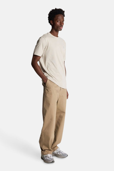Lichtgrijs T-shirt met korte mouwen van LYLE & SCOTT, gedragen met een beige broek en grijze sneakers, zijwaarts bekeken.