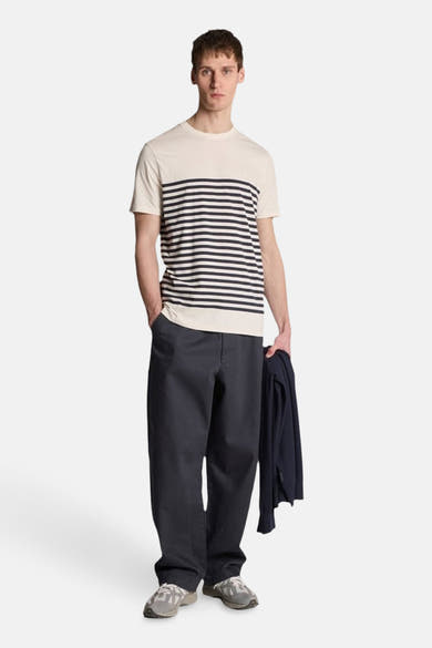 T-shirt à manches courtes blanc rayé de LYLE & SCOTT, porté avec un pantalon bleu marine et des baskets grises.