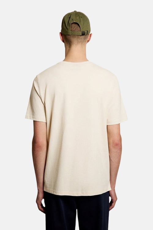 T-shirt à manches courtes écru de LYLE & SCOTT, porté avec une casquette vert olive vue de dos.