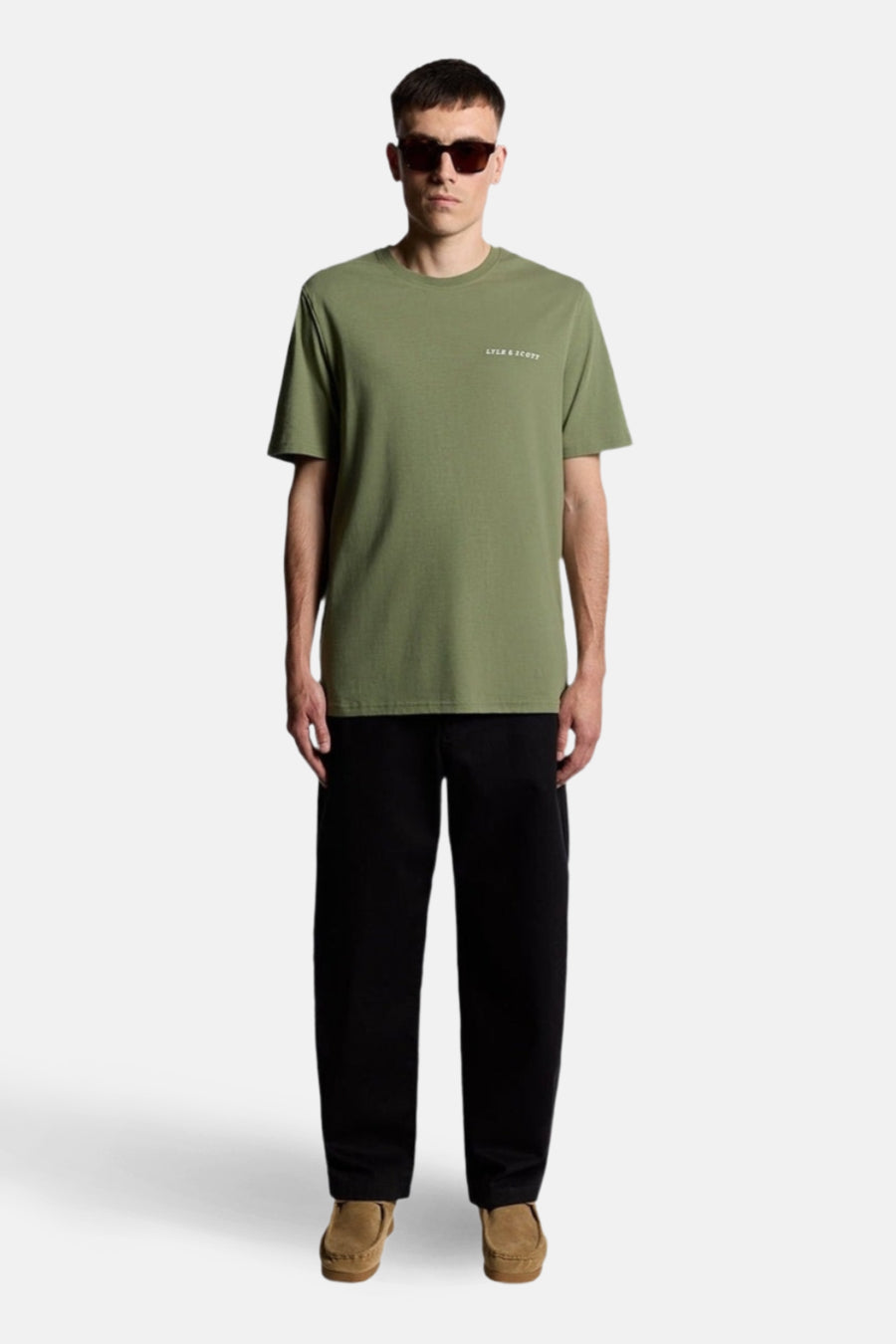 Groen T-shirt met korte mouwen van LYLE & SCOTT, gedragen met een zwarte broek en bruine loafers.