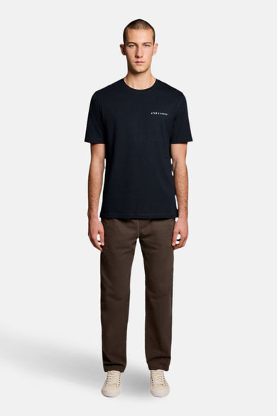 T-shirt à manches courtes bleu de LYLE & SCOTT, porté avec un pantalon marron et des baskets blanches.