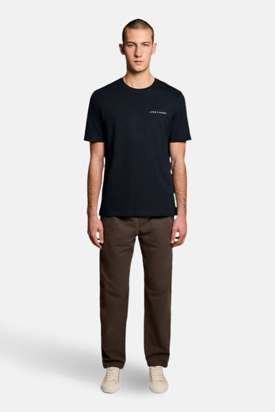 T-shirt à manches courtes bleu de LYLE & SCOTT, porté avec un pantalon marron et des baskets blanches.