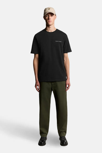 T-shirt noir à manches courtes de LYLE & SCOTT, porté avec un pantalon vert olive et une casquette beige.