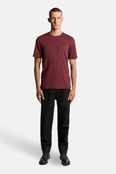 Bordeaux T-shirt met korte mouwen van LYLE & SCOTT, gedragen met een zwarte broek en bijpassende schoenen.