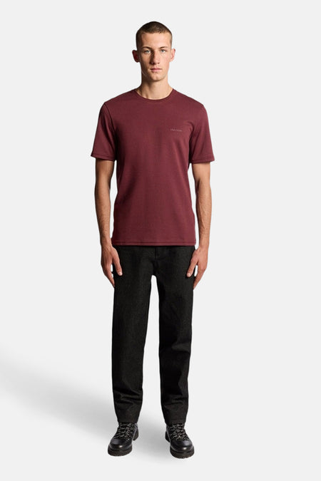 Bordeaux T-shirt met korte mouwen van LYLE & SCOTT, gedragen met een zwarte broek en bijpassende schoenen.