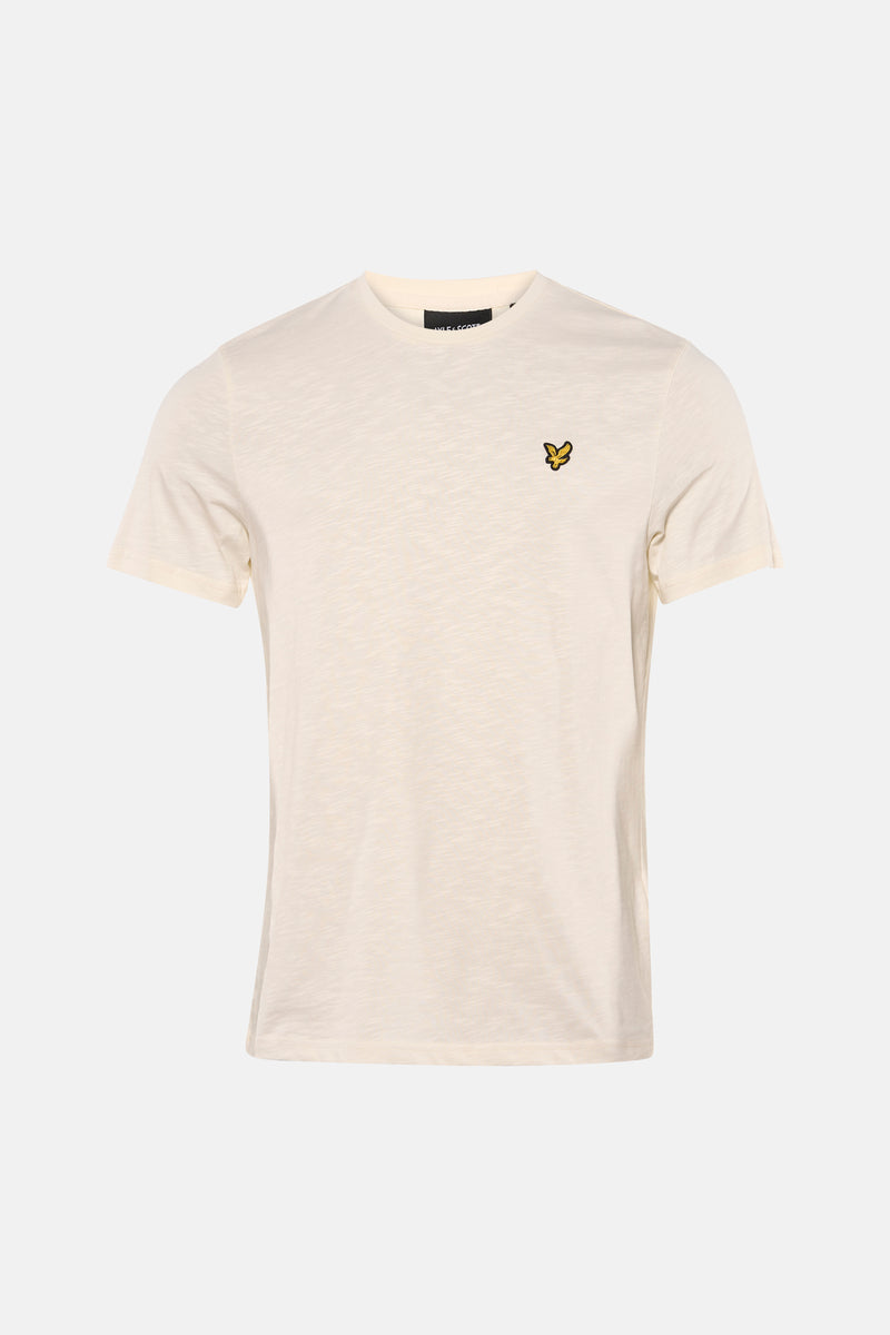 Ecru T-shirt met korte mouwen van LYLE & SCOTT, gedragen met een bruine broek en suède loafers.