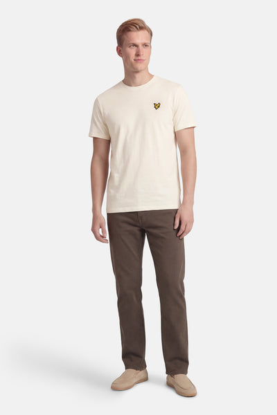 T-shirt à manches courtes écru de LYLE & SCOTT, porté avec un pantalon marron et des mocassins en daim.