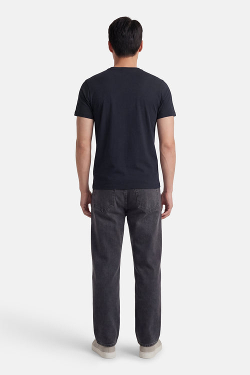 T-shirt à manches courtes bleu de LYLE & SCOTT, vu de dos, porté avec un jean gris et des chaussures couleur crème.
