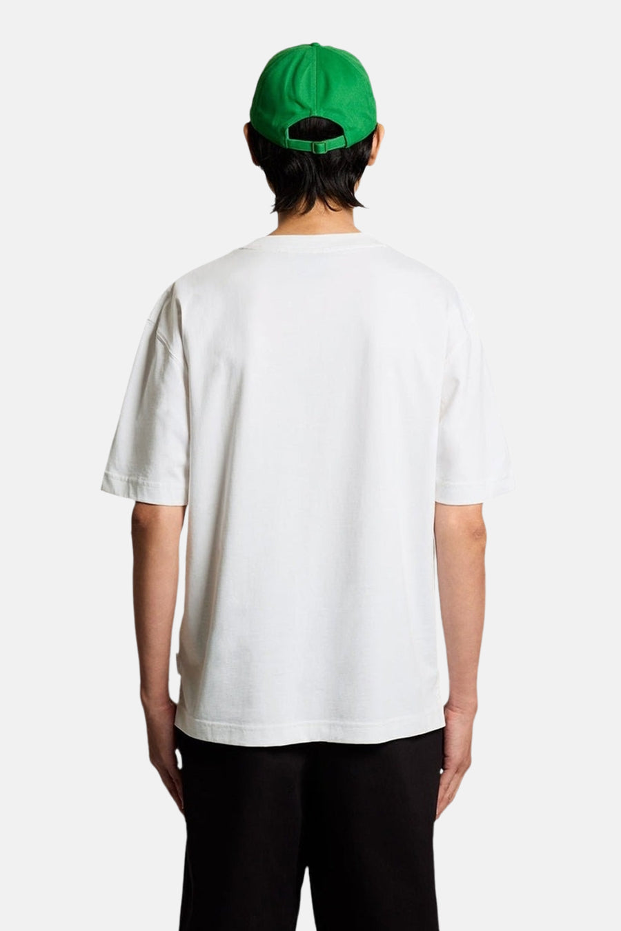 T-shirt blanc de LYLE & SCOTT, vue de dos, porté avec une casquette verte et un pantalon noir.