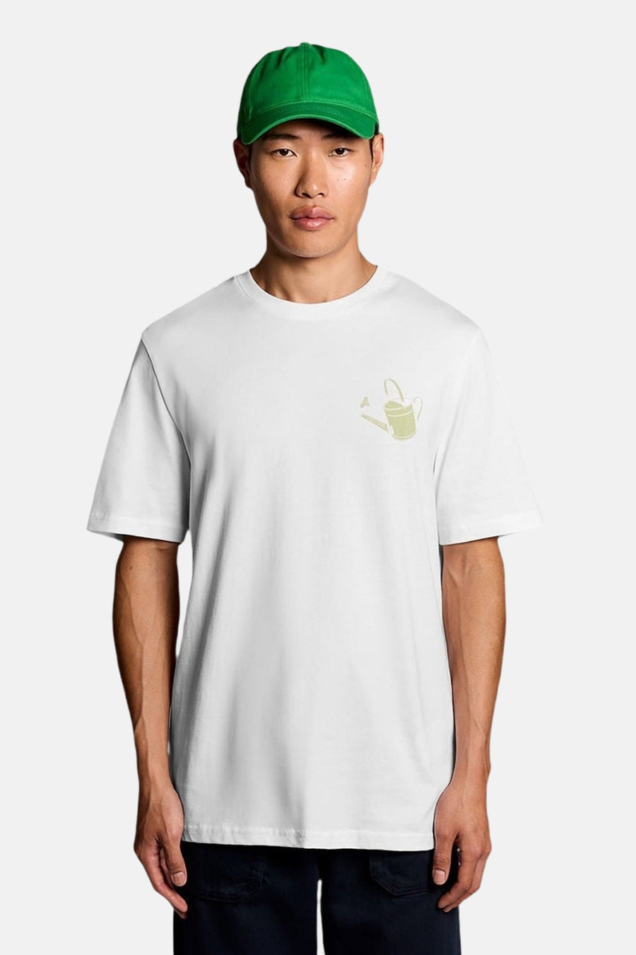 Wit T-shirt van LYLE & SCOTT met een lichtgroen gieterpatroon, gedragen door een man met een groene pet.