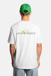 Wit T-shirt van LYLE & SCOTT met bloemen "LS"-logo, gedragen met een lichte spijkerbroek, loafers en een groene pet.