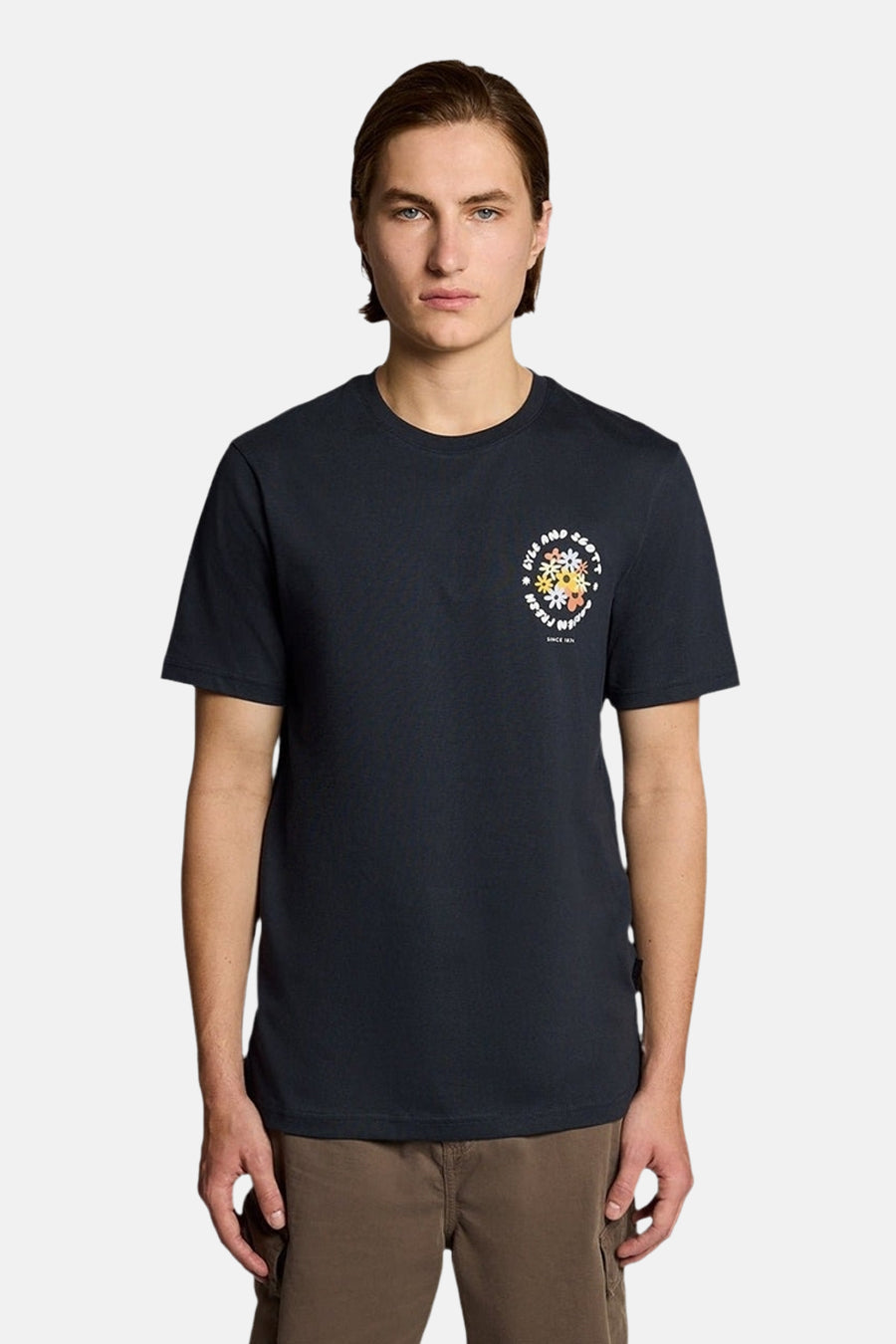 T-shirt bleu marine à manches courtes de LYLE & SCOTT avec un motif floral circulaire sur la poitrine, porté par un homme.
