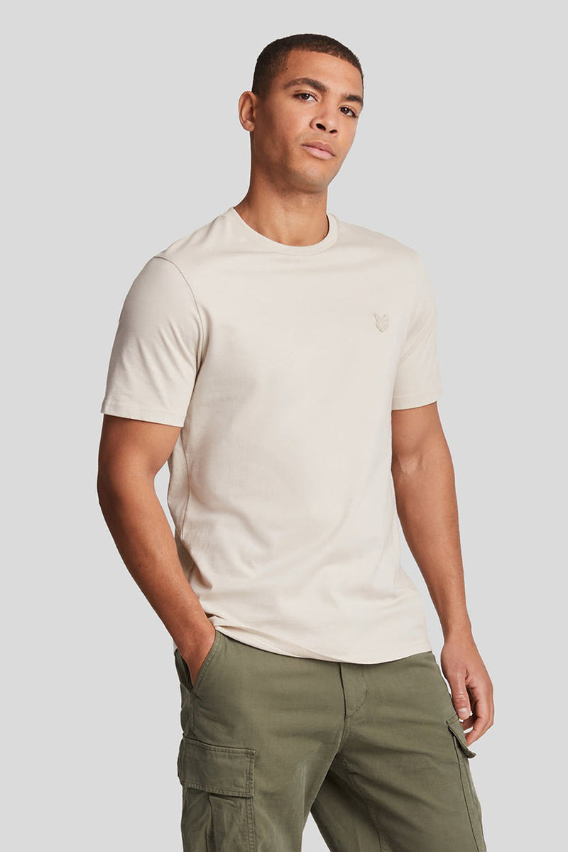 T-shirt à manches courtes beige de LYLE & SCOTT, porté avec un pantalon cargo olive.