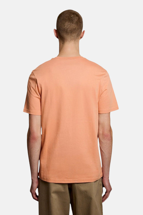 T-shirt orange uni de LYLE & SCOTT, vue de dos, porté par un homme avec un short kaki.