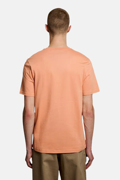 T-shirt orange uni de LYLE & SCOTT, vue de dos, porté par un homme avec un short kaki.