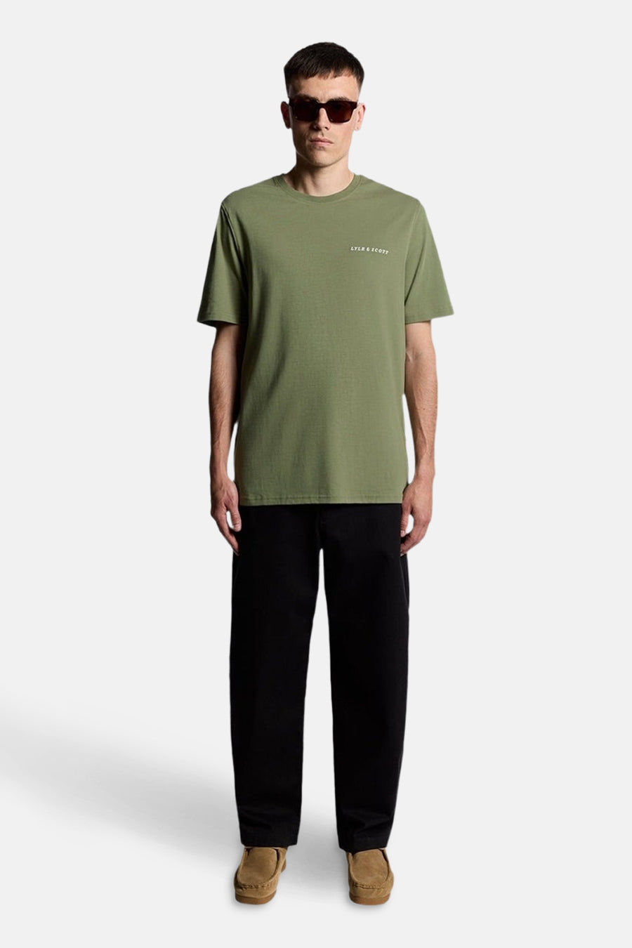 Groen T-shirt met korte mouwen van LYLE & SCOTT, gedragen met een zwarte broek en bruine loafers.