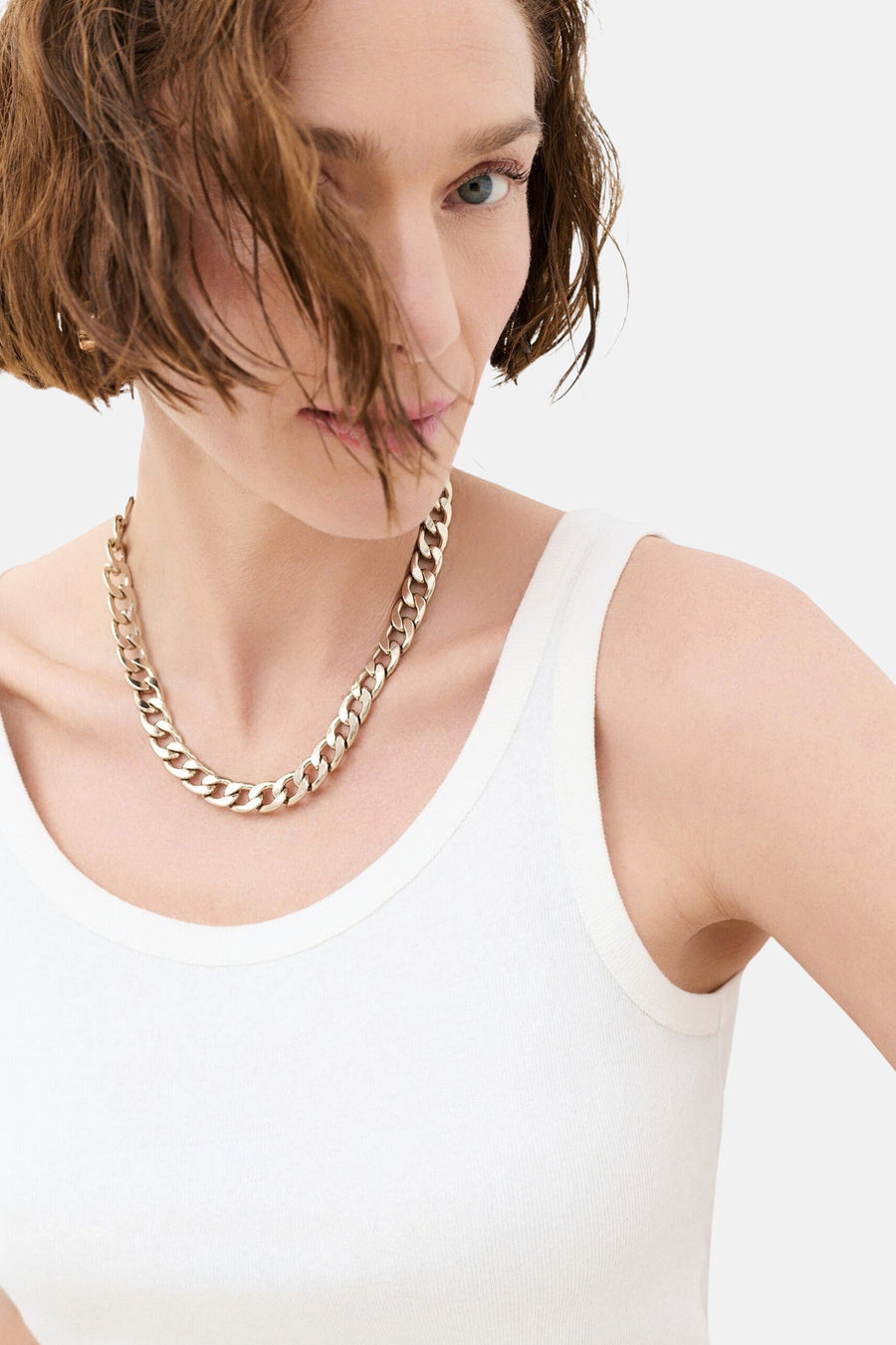 Ecru mouwloos topje van CAROLL, geribd, gedragen met een gouden ketting.