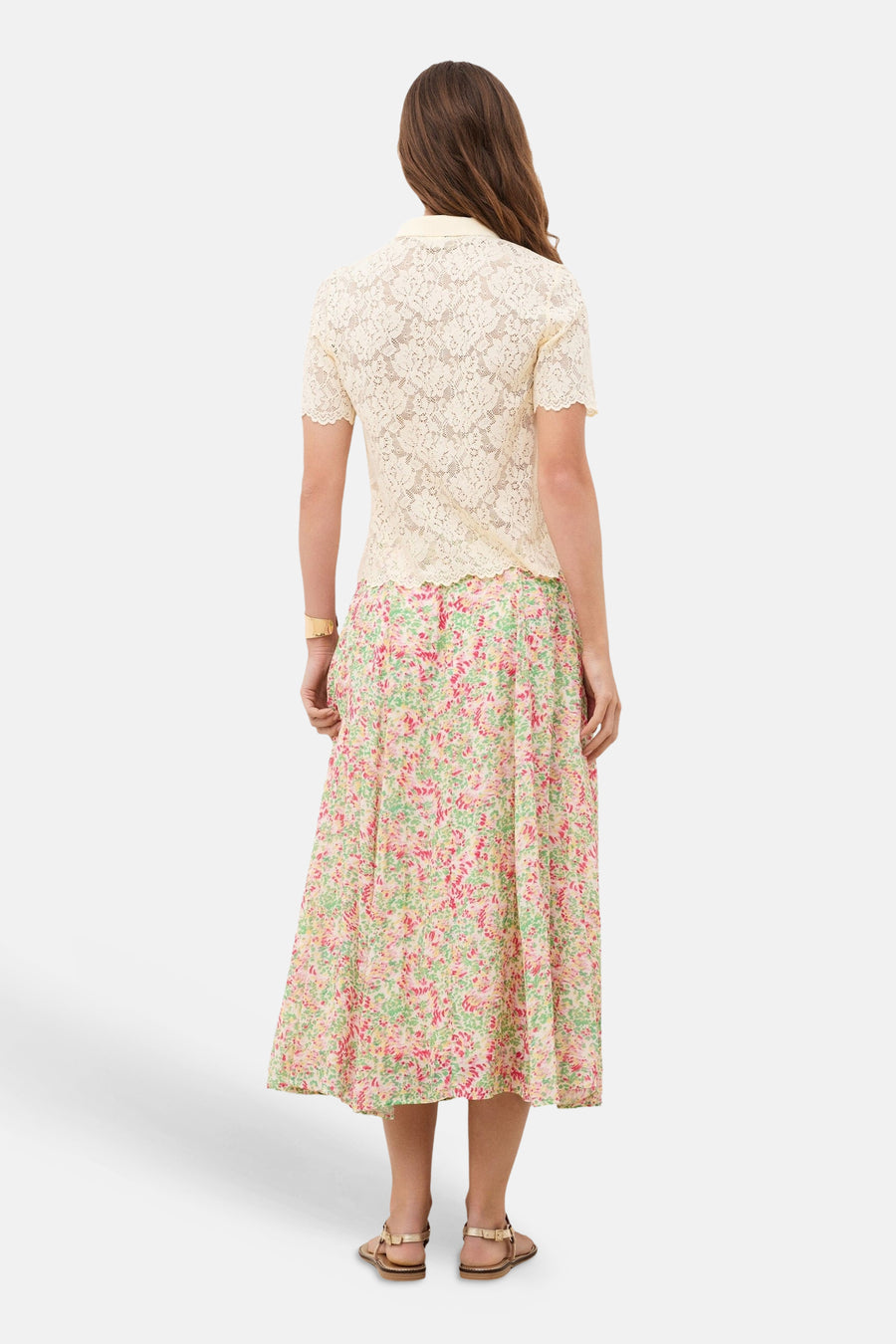 Polo jaune de CAROLL en dentelle à manches courtes, porté de dos avec une jupe fleurie.