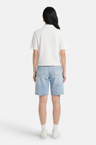 Polo blanc de CAROLL, manches courtes, porté avec un short en jean et des baskets blanches, vue de dos.