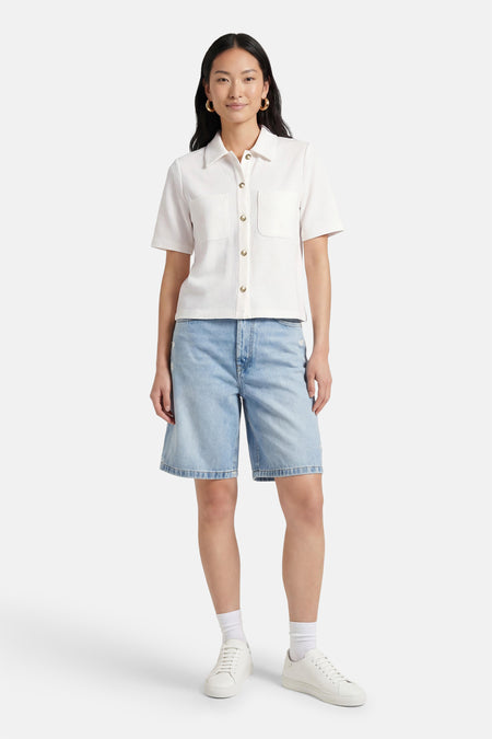 Wit CAROLL poloshirt, korte mouwen, gedragen met een blauwe spijkerbroek en witte sneakers.