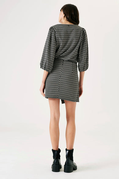 Jupe courte noire GARCIA à motifs imprimés, coupe portefeuille asymétrique et bottines noires à talons.
