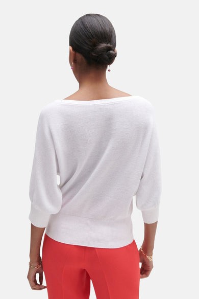 Witte rondehals trui van CAROLL, driekwart pofmouwen, gedragen met een rode broek.